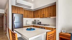 A modern kitchen with wooden cabinets, a stainless steel refrigerator, and a central island with seating. - Serene Coastal Getaway With Private Infinity Pool, Beach Access & Scenic Vistas (Puerto Vallarta)