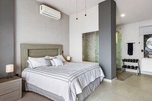 Un dormitorio moderno con una cama grande, mesitas de noche, un equipo de aire acondicionado y una estantería de pared con mancuernas.