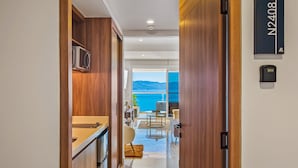 A modern hotel corridor with wooden walls, a kitchen area, and a view of the sea. - Oceanfront Studio With Infinity Pool, Breathtaking Views & Beach Access (Puerto Vallarta)