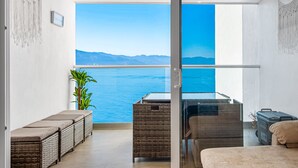 A balcony with a view of the sea, wicker furniture, a glass table, and a potted plant. - Oceanfront Studio With Infinity Pool, Breathtaking Views & Beach Access (Puerto Vallarta)