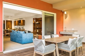 Ein modernes Wohnzimmer mit einem blauen Sofa, Korbstühlen und einem Holzes Esstisch.