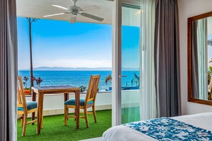 A hotel room with a balcony, a ceiling fan, a bed with a patterned bedspread, and a view of the ocean. - Exquisite Waterfront Condo With Amazing Pool, Balcony & W/D (Puerto Vallarta)