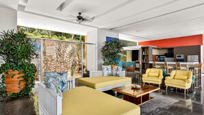 A modern living room with a stone wall, yellow sofas, and potted plants. - Modern Condo With Ocean Views, Rooftop Infinity Pool & Central AC (Puerto Vallarta)