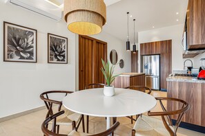 A modern kitchen with wooden cabinets, a white dining table, and two framed succulent plant artworks. - D'toscana Residencial, PH #11 Condo in Nuevo Vallarta With Rooftop Pool (Nuevo Nayarit)
