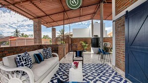 An outdoor patio with a white sofa, blue patterned rug, and a wooden table. - Authentic Mexican Hacienda: 1BR w/ Outdoor Kitchen, A/C & Fast Wi-fi in Bucerias (Bucerías)