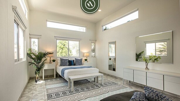 A bedroom with a bed, bedside tables, a bench, a dresser, a mirror, and a large window. - Authentic Mexican Hacienda: 1BR w/ Outdoor Kitchen, A/C & Fast Wi-fi in Bucerias (Bucerías)