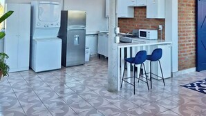 A compact kitchen with a washing machine, a microwave, and a gas stove. - Authentic Mexican Hacienda: 1BR w/ Outdoor Kitchen, A/C & Fast Wi-fi in Bucerias (Bucerías)