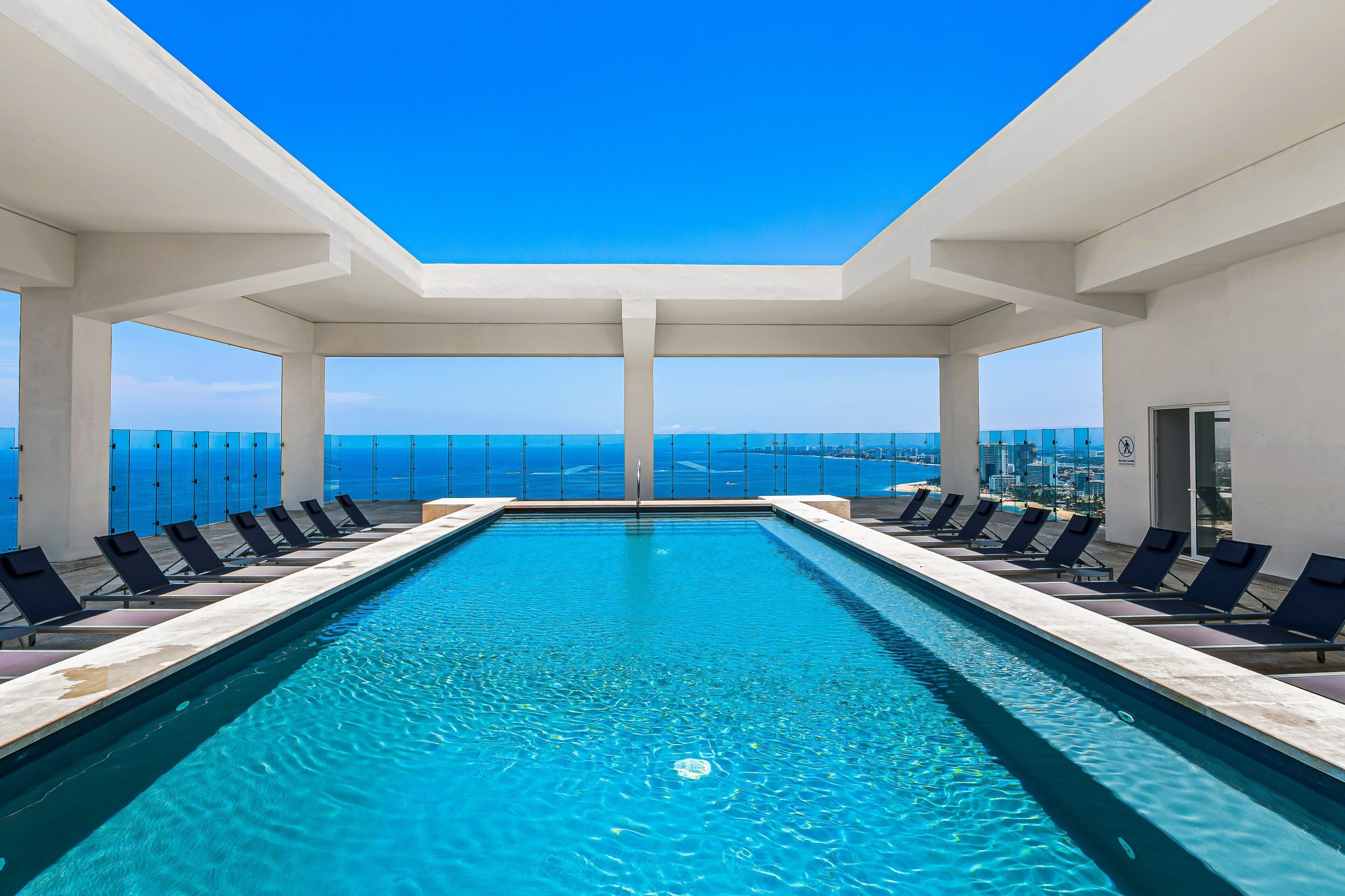 Une piscine avec des chaises longues et vue sur l’océan.