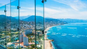 A coastal cityscape with a beach, mountains, and a clear sky. - Stylish Oceanfront Condo With Infinity Pool, Rooftop Deck & Beach Access (Puerto Vallarta)