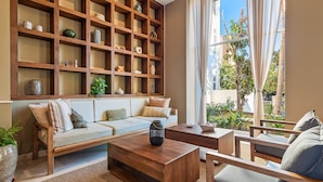 A living room with a sofa, coffee table, and shelves filled with decorative items. - Modern Oceanfront Studio With Breathtaking Sunsets, Heated Pools & Beach Access (Puerto Vallarta)
