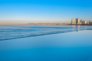 A coastal cityscape with a clear view of the sea and a row of high-rise buildings. - Modern Oceanfront Studio With Breathtaking Sunsets, Heated Pools & Beach Access (Puerto Vallarta)