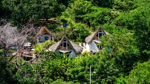 A cluster of thatched-roof cottages nestled among lush greenery. - Relaxing Apartment With Mini Pool & High-speed Internet - Explore Local Delights (La Culebra)