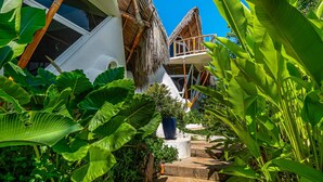 A tropical resort with a thatched-roof structure, a white exterior, and lush greenery. - Relaxing Apartment With Mini Pool & High-speed Internet - Explore Local Delights (La Culebra)