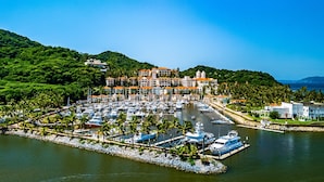 A marina with boats docked, surrounded by lush greenery and a large building with multiple balconies. - Relaxing Apartment With Mini Pool & High-speed Internet - Explore Local Delights (La Culebra)