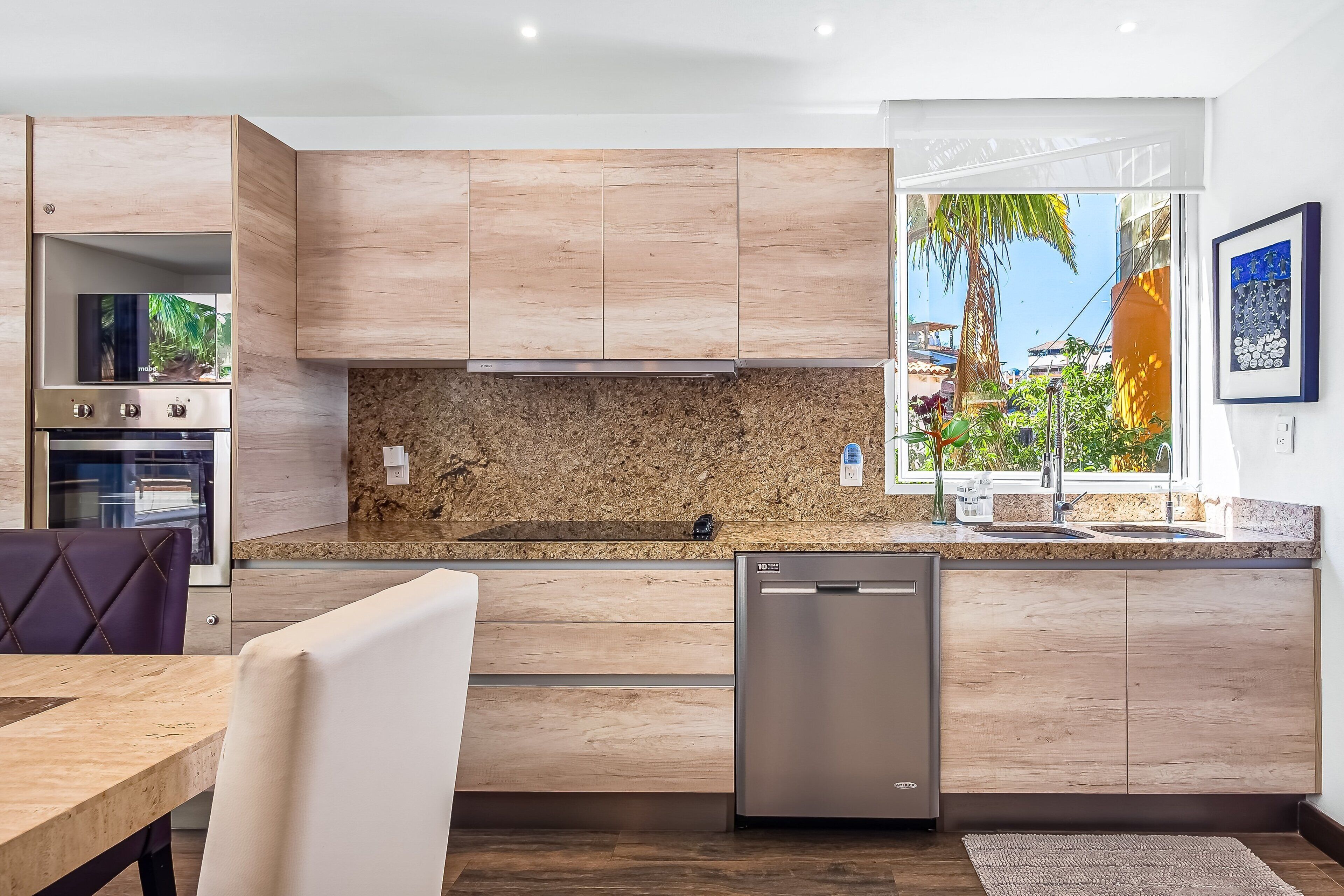 Eine moderne Küche mit Holzschränken, einer Granit-Arbeitsplatte und einem integrierten Geschirrspüler.