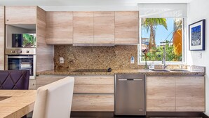 Una cucina moderna con mobili in legno, un piano di lavoro in granito e una lavastoviglie integrata.