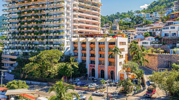 Un hotel a più piani con balconi, un'area parcheggio e vista sugli edifici circostanti.