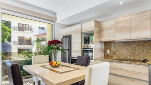 Una cucina moderna con un piano di lavoro in marmo, mobili integrati e un'area pranzo con tavolo e sedie.