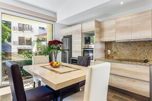 A modern kitchen with a marble countertop, built-in cabinets, and a dining area with a table and chairs. - Stunning Condo With Brilliant Views, Walk-in Shower, Desk, Balcony, & W/D (Puerto Vallarta)