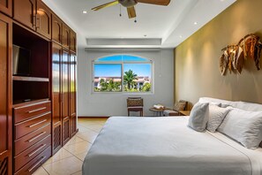 A bedroom with a large bed, a ceiling fan, a TV, a window with a view, and a wardrobe. - Cozy Condo With Loft, Private Balcony and Gorgeous Shared Pool (Nuevo Nayarit)