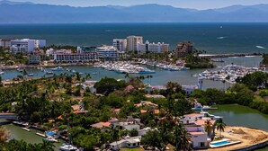 A marina with boats, buildings, and a clear view of the sea and mountains in the background. - Cozy Condo With Loft, Private Balcony and Gorgeous Shared Pool (Nuevo Nayarit)