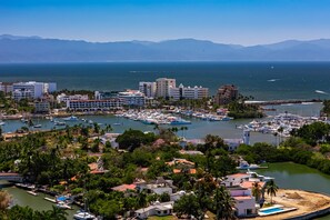 A marina with boats, buildings, and a clear view of the sea and mountains in the background. - Cozy Condo With Loft, Private Balcony and Gorgeous Shared Pool (Nuevo Nayarit)