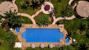 An aerial view of a swimming pool surrounded by palm trees, sun loungers, and covered areas. - Cozy Condo With Loft, Private Balcony and Gorgeous Shared Pool (Nuevo Nayarit)