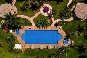 An aerial view of a swimming pool surrounded by palm trees, sun loungers, and covered areas. - Cozy Condo With Loft, Private Balcony and Gorgeous Shared Pool (Nuevo Nayarit)