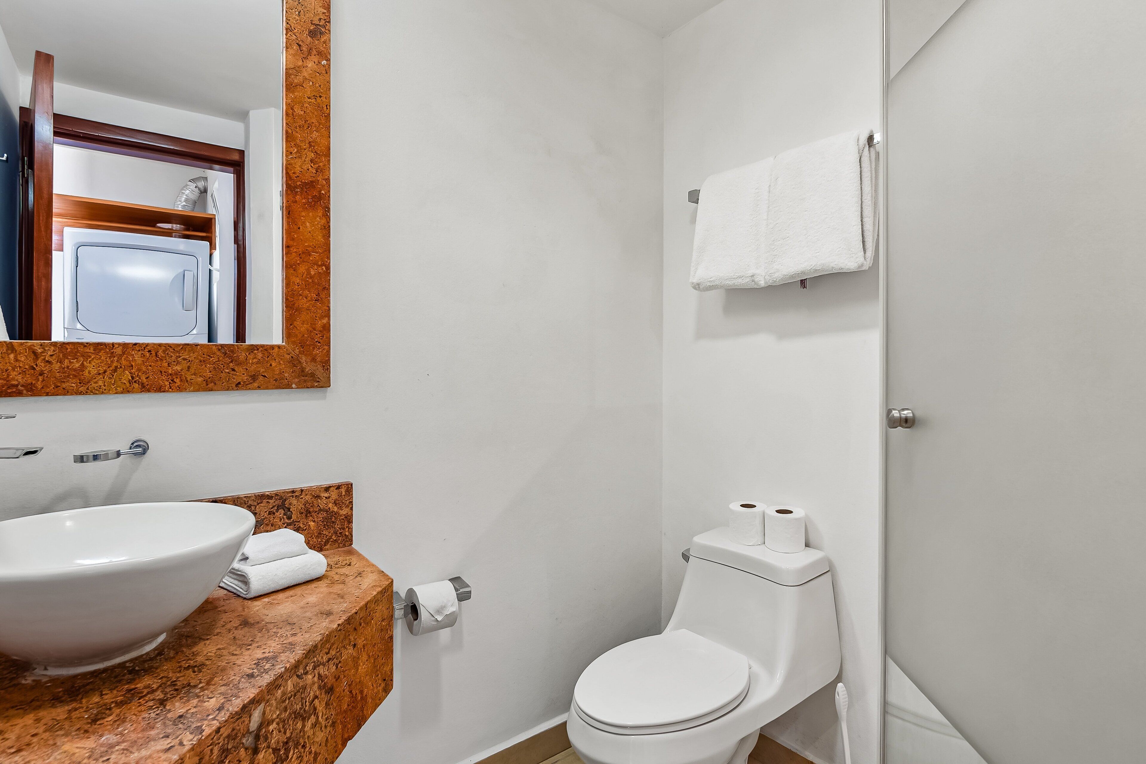 A bathroom with a white sink, a toilet, and a towel hanging on the wall.