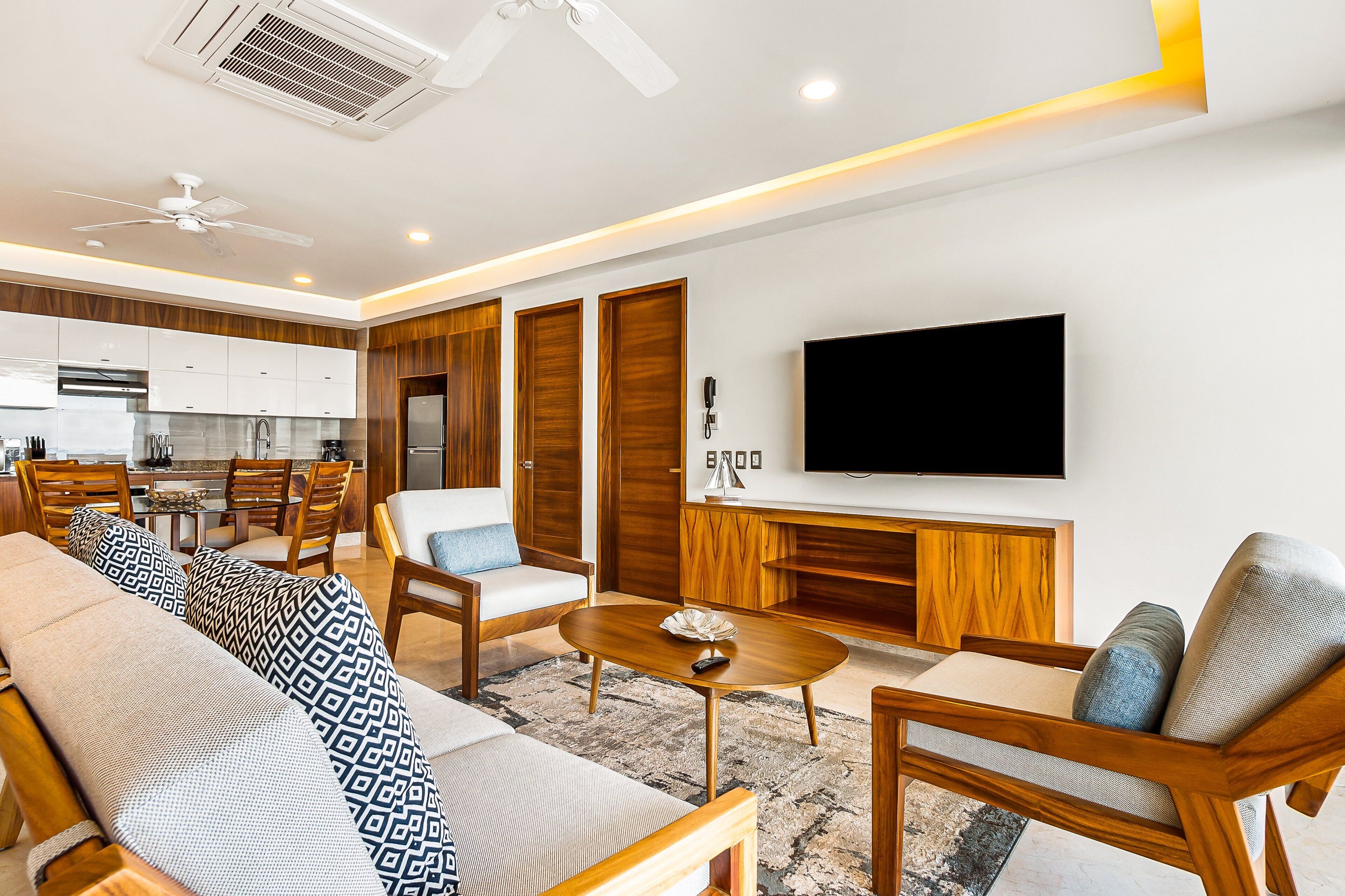 A modern living room with a sofa, chairs, a coffee table, and a TV.