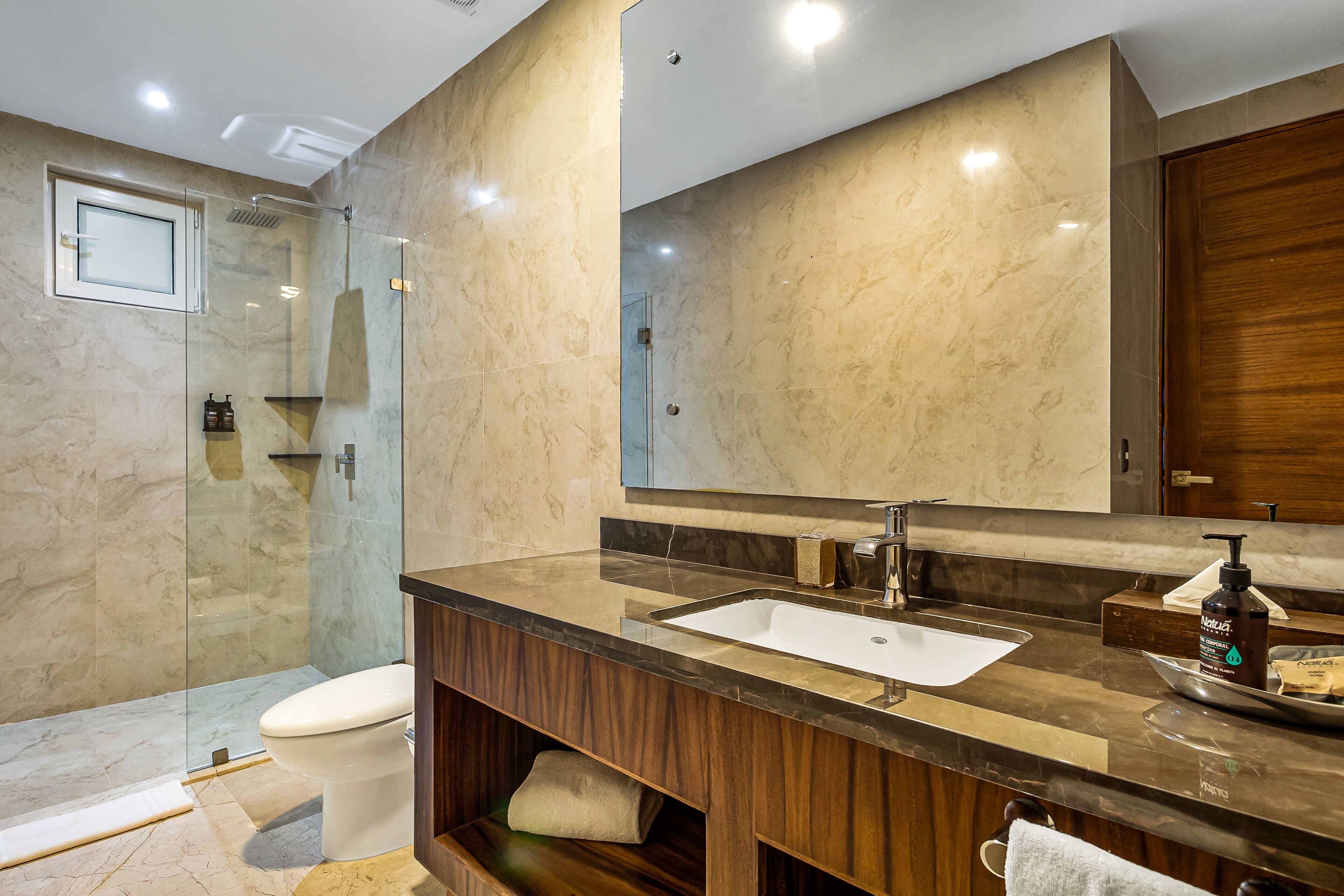 A modern bathroom with a glass-enclosed shower, a wooden vanity with a sink, and a large mirror.