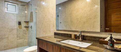 A modern bathroom with a glass-enclosed shower, a wooden vanity with a sink, and a large mirror.