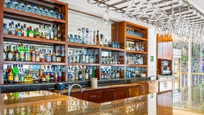 A bar with multiple shelves of liquor bottles, a polished granite countertop, and a modern ceiling design. - Spacious Suite With Wraparound Terrace, Rooftop Infinity Pool & Resort Amenities (Puerto Vallarta)