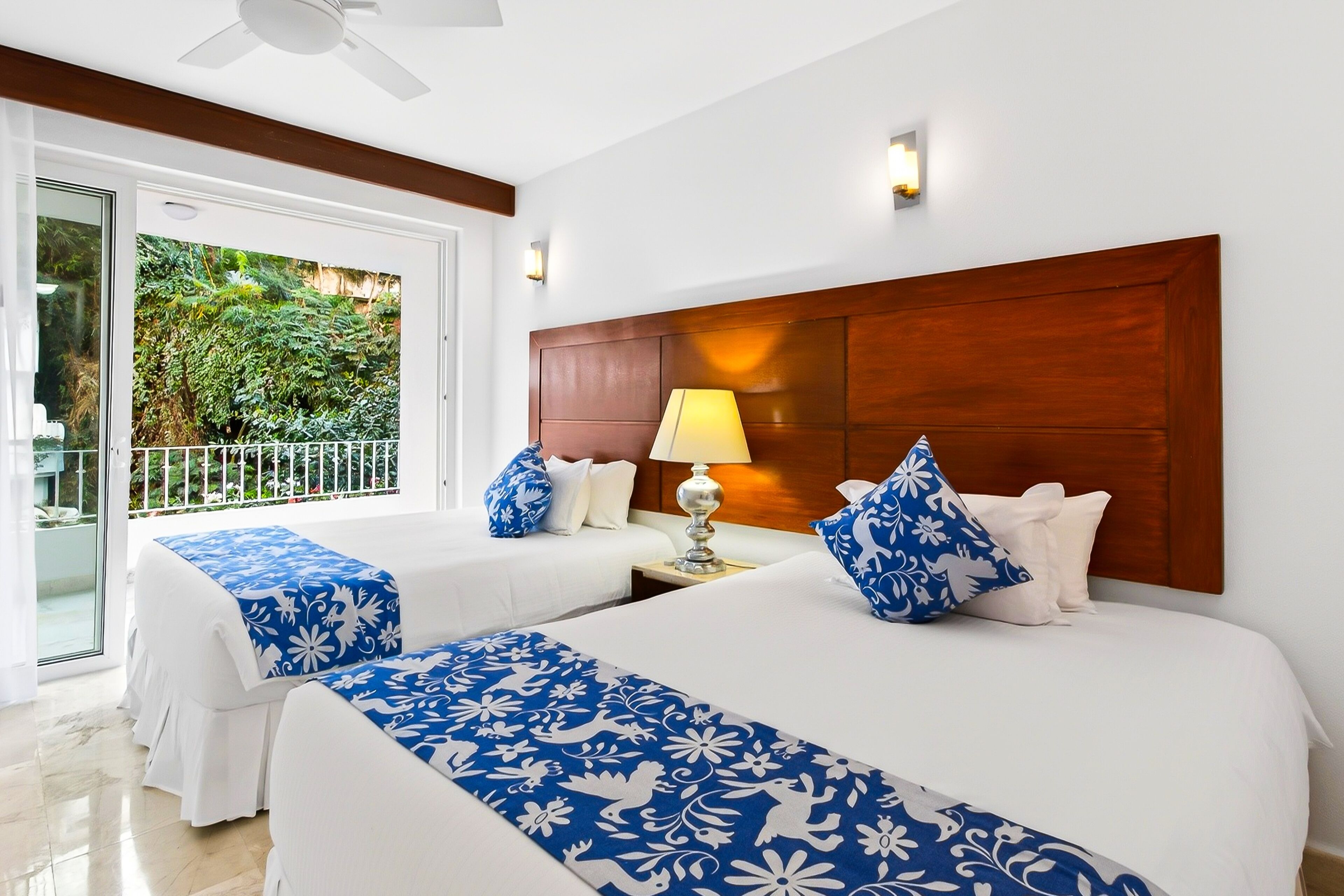 Une chambre d’hôtel avec deux lits, un balcon et une tête de lit en bois.