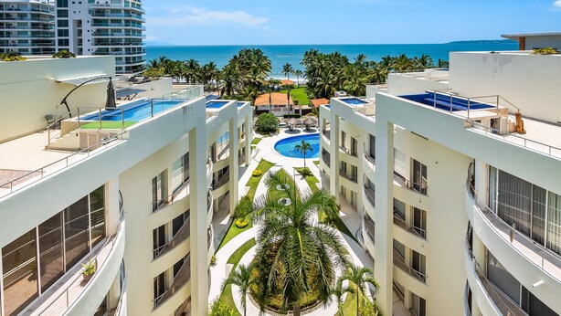 A multi-story hotel with balconies, a swimming pool, and a view of the ocean. - Ocean-view Condo With Resort Pool & Sundeck (Nuevo Nayarit)