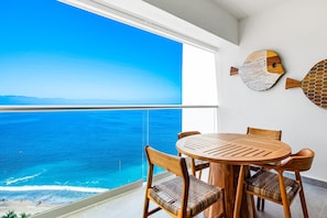 Un balcón con vista al océano, muebles de madera y un mural decorativo con peces.