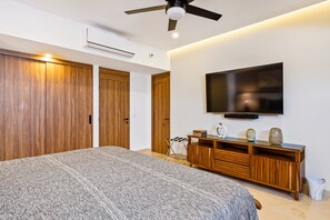 A bedroom with a bed, wardrobe, TV, and a ceiling fan. - Luxury Oceanfront Apartment With Private Balcony, Rooftop Pool & gym Access (Puerto Vallarta)