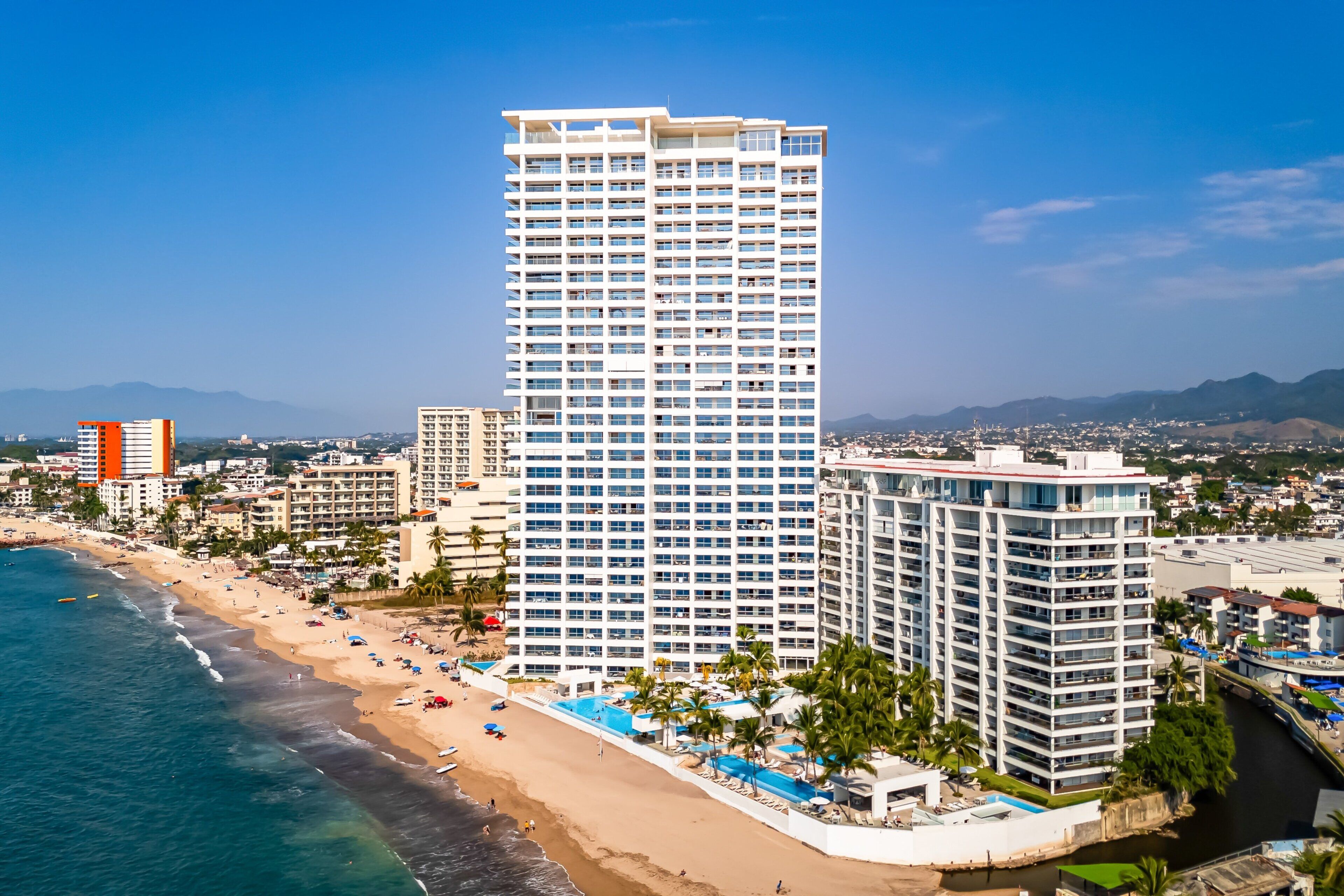 A high-rise hotel with multiple floors, a beachside location, and a pool area.