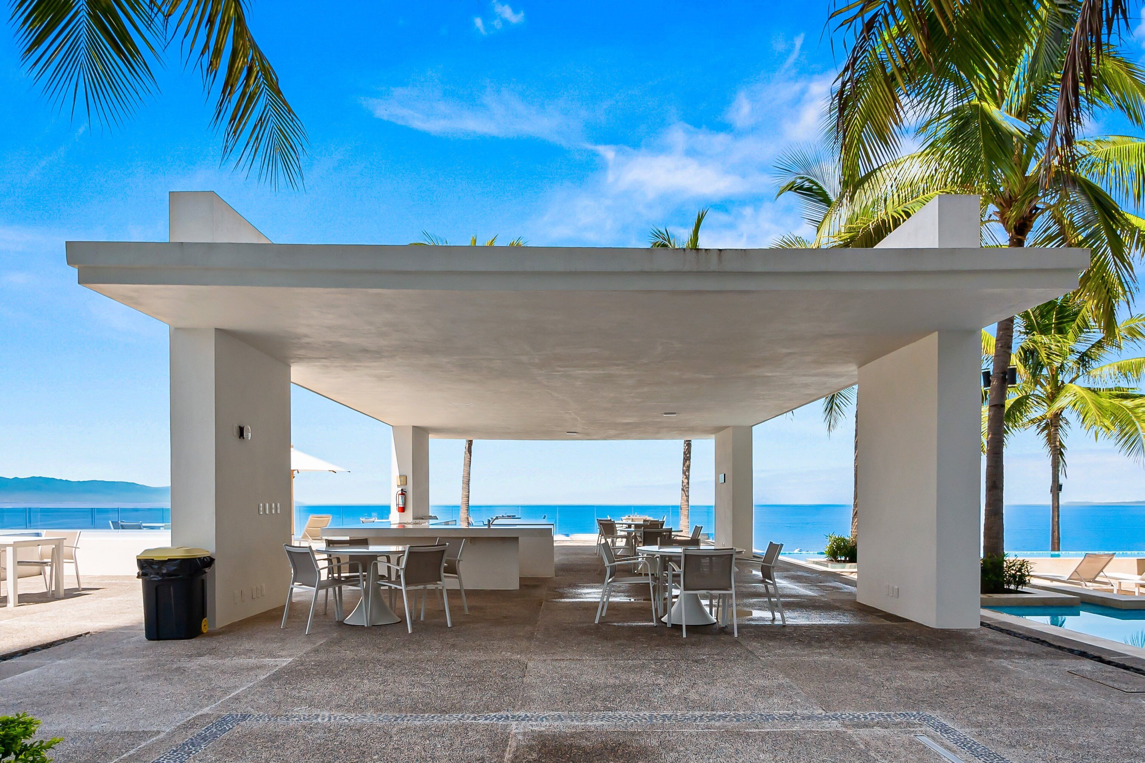 An outdoor patio with a pool, seating, and a view of the ocean.