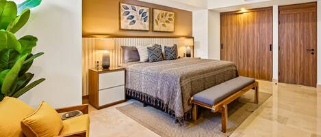 A modern bedroom with a bed, bedside tables, a bench, a ceiling fan, and a large green plant.