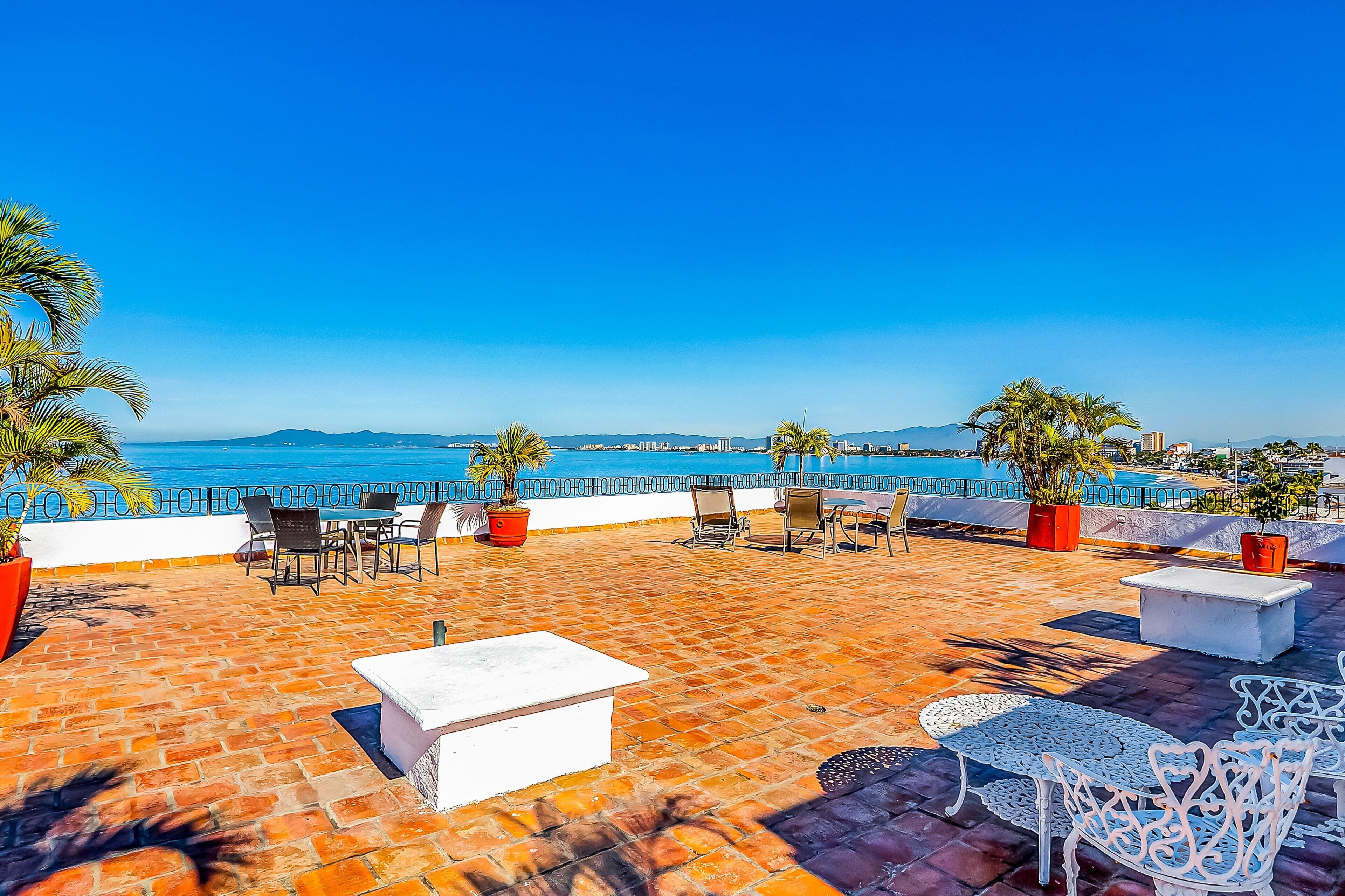 Una terrazza con posti a sedere all'aperto, vista sul mare e palme.