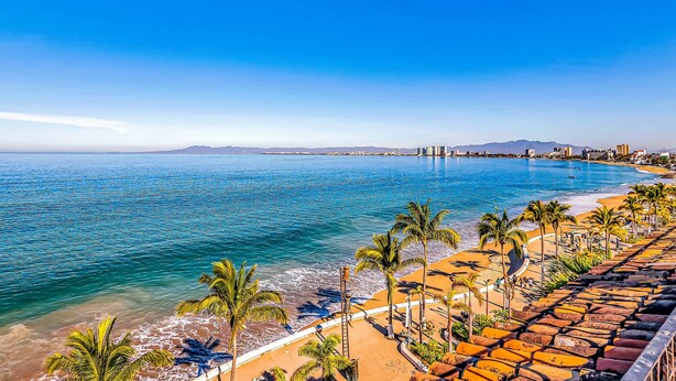Ein Küstenort mit Strand, Palmen und Blick auf den Ozean.