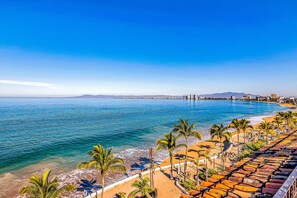 A coastal resort with a beach, palm trees, and a view of the ocean. - Downtown Malecon Beach Front, AC, Walk to Restaurant/bars, Rooftop 360 Views (Puerto Vallarta)