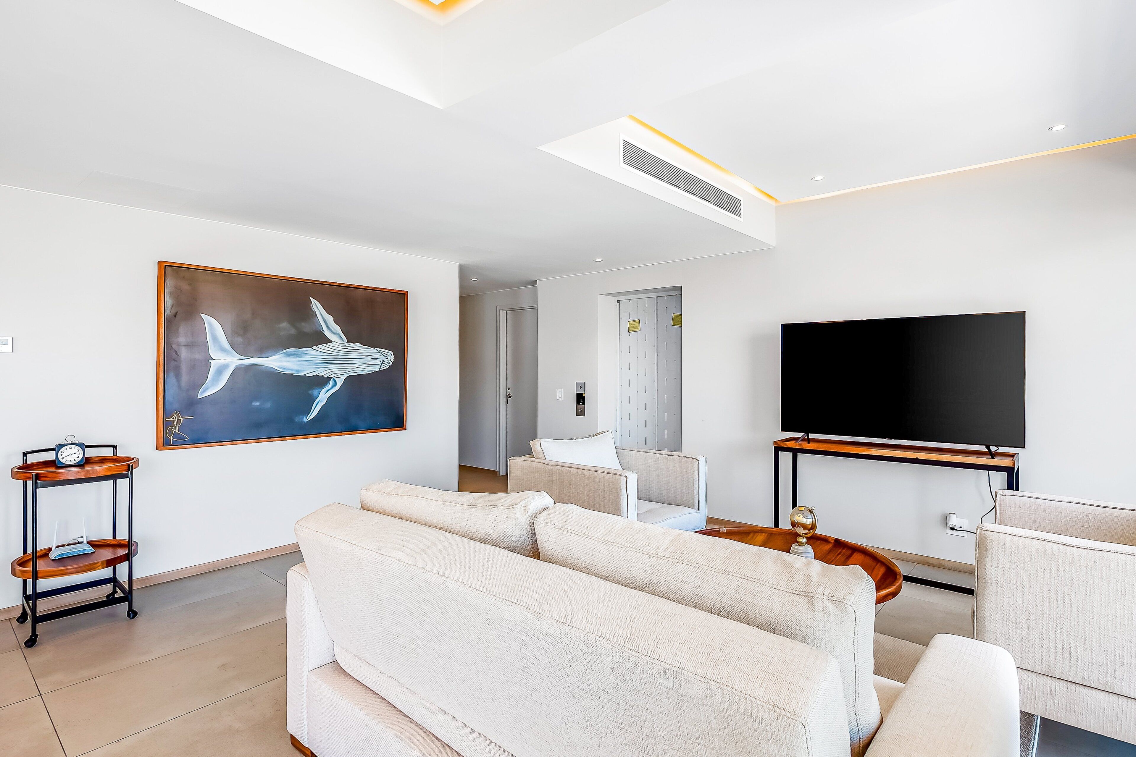 Un salon moderne avec un grand téléviseur à écran plat, un canapé, une table basse et un tableau accroché au mur.