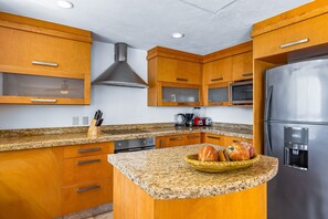 Eine Küche mit Holzausstattung, Granit-Arbeitsplatten, einem Edelstahl-Kühlschrank und einer Mikrowelle.