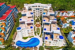 Ein mehrstöckiges Hotel mit einem zentral gelegenen Pool, Balkonen und einem umlaufenden Garten.