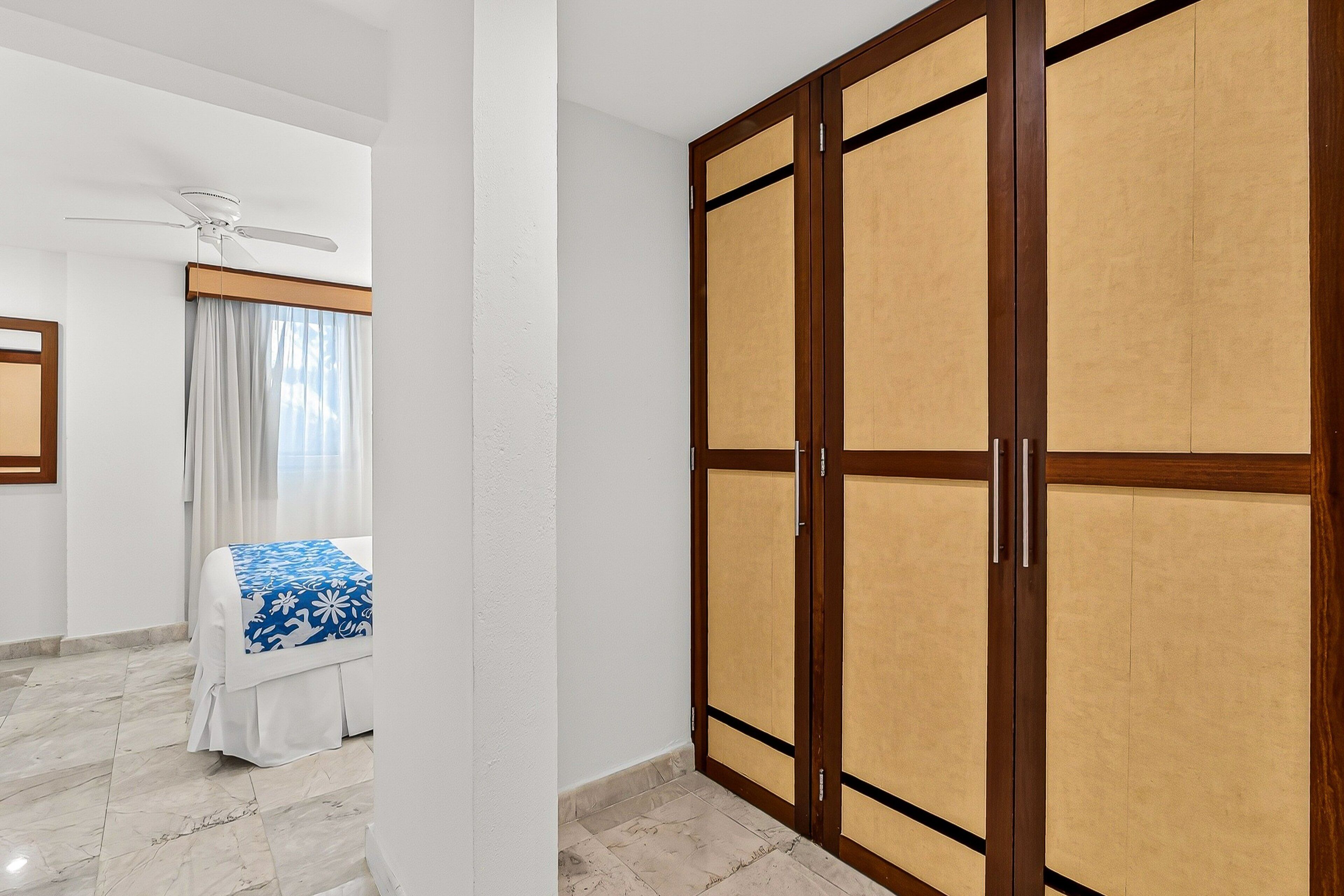 Quarto de hotel com cama, ventoinha no teto e guarda-roupa.