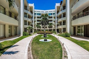A multi-story building with a central courtyard, a fountain, and a palm tree. - 2nd-floor Condo With Private Balcony, On-site Pool & Billiards (Nuevo Nayarit)