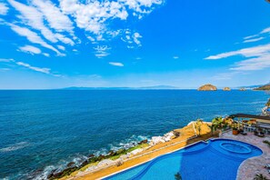 A pool with a view of the ocean and distant mountains. - Exceptional Waterfront Condo With Pool, Balcony, Fitness Area, & W/D (Puerto Vallarta)