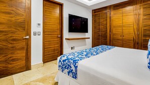 A bedroom with a bed, wooden wardrobes, a mounted TV, and a built-in shelf. - Exceptional Waterfront Condo With Pool, Balcony, Fitness Area, & W/D (Puerto Vallarta)